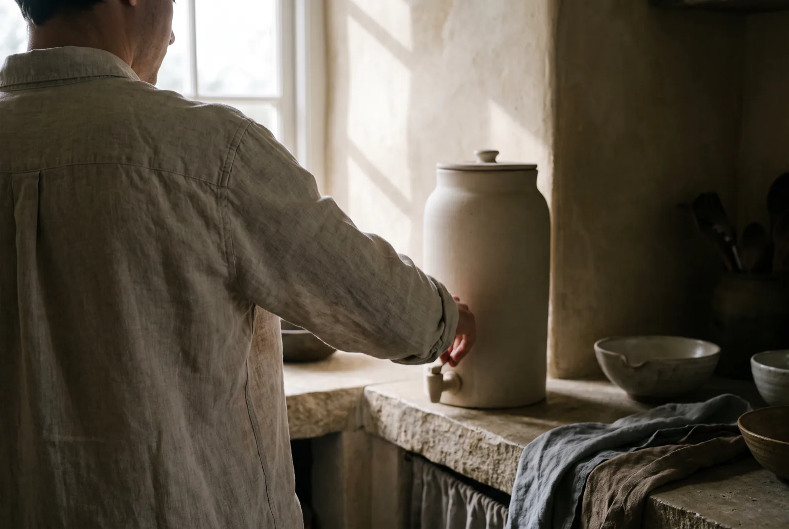 Filling a stoneware countertop filter in morning light