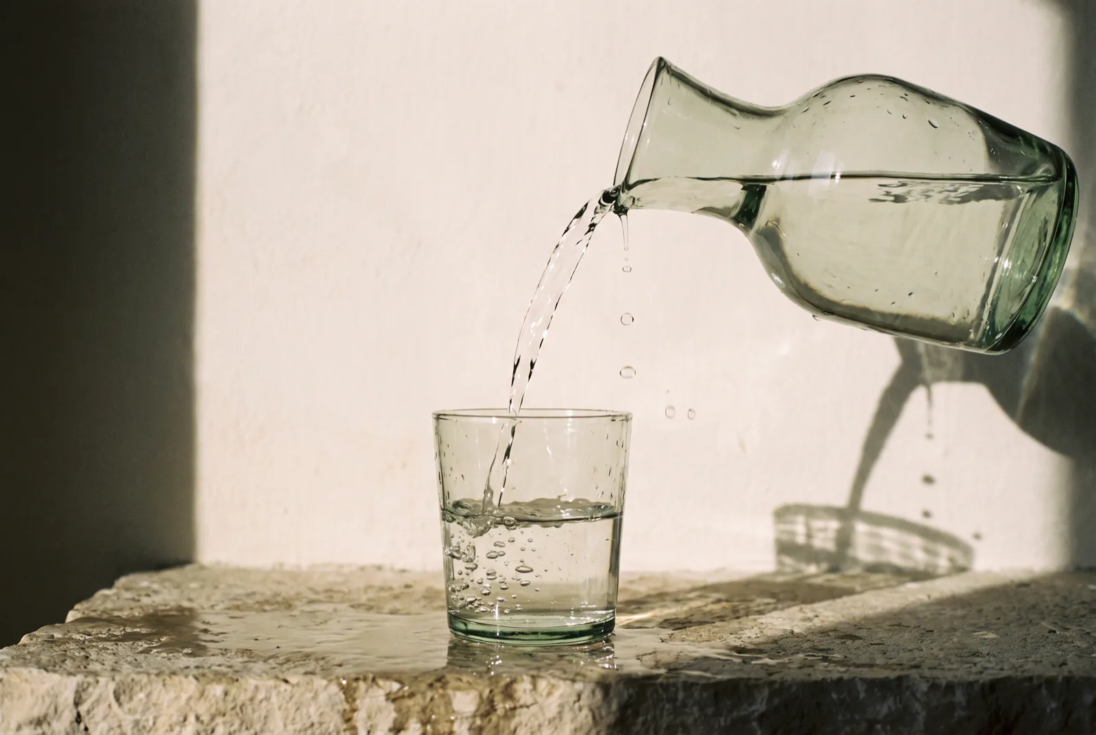 Water poured from a glass carafe into a tumbler